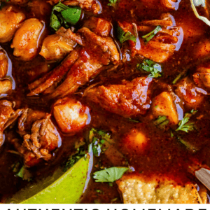 close up of pork and hominy in rich red broth and cabbage.
