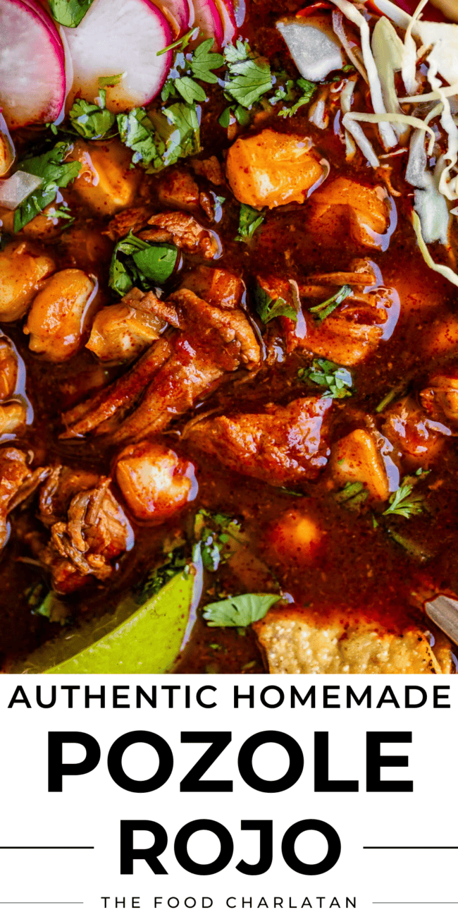close up of pork and hominy in rich red broth and cabbage.