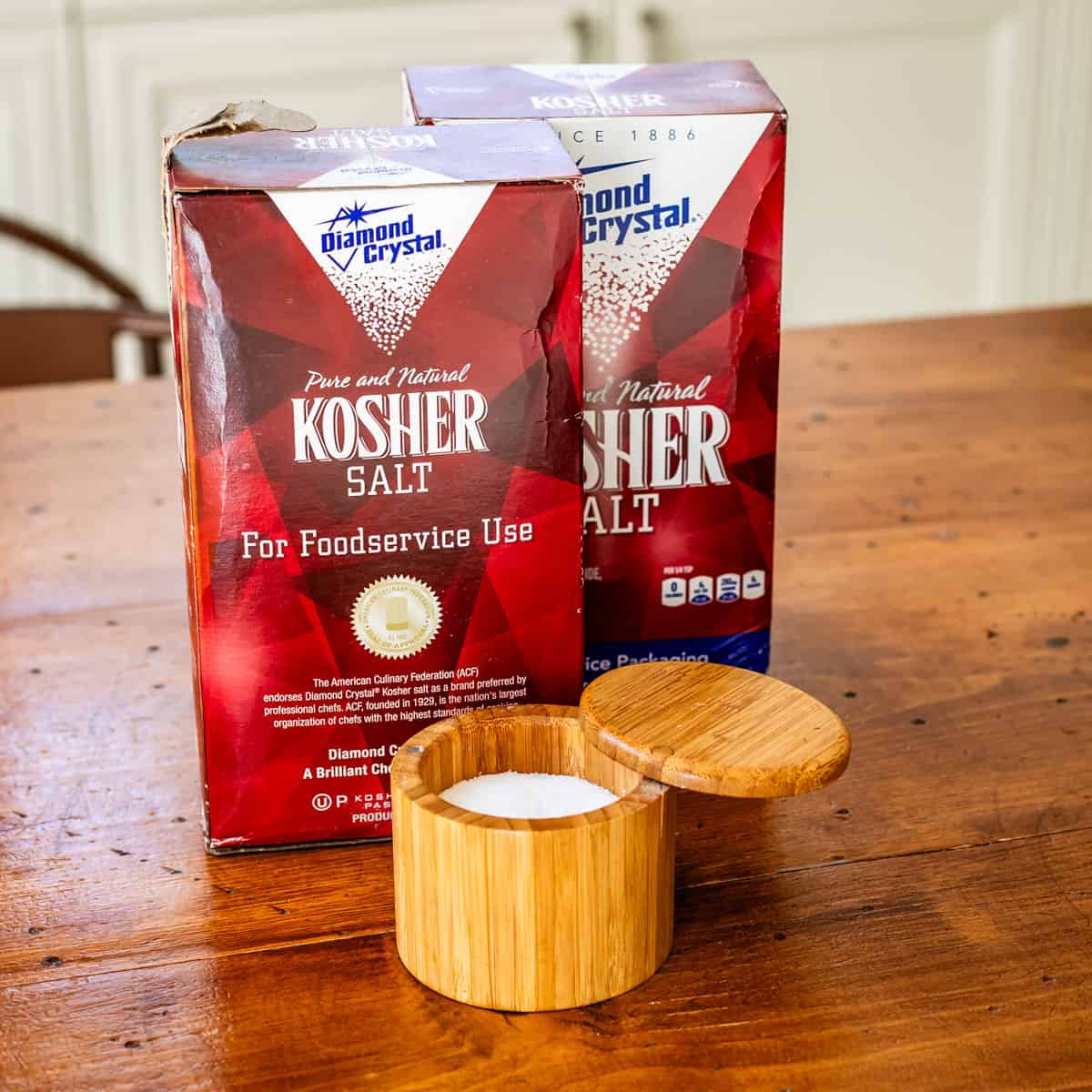 Diamon Crystal kosher salt boxes with salt container on wooden table.