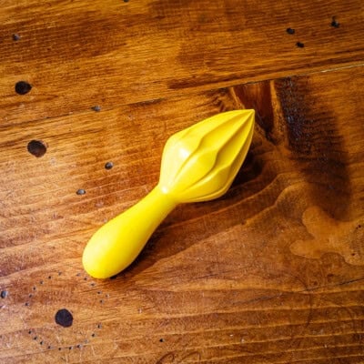 Yellow citrus reamer on wooden table.