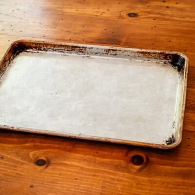 Well-used half sheet baking pan on wooden table.