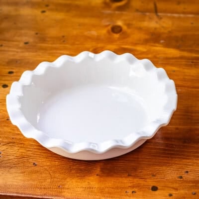 White ceramic pie plate on wooden table.
