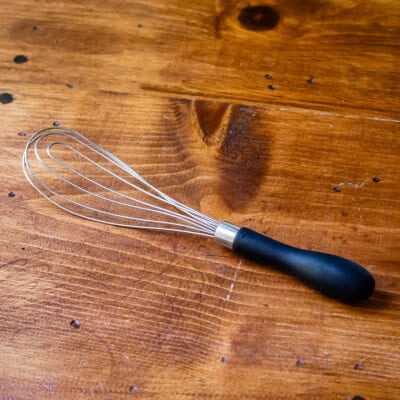 Flat whisk on wooden table.