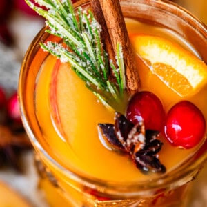 looking into the top of a glass of wassail topped with orange, cranberry, and more.