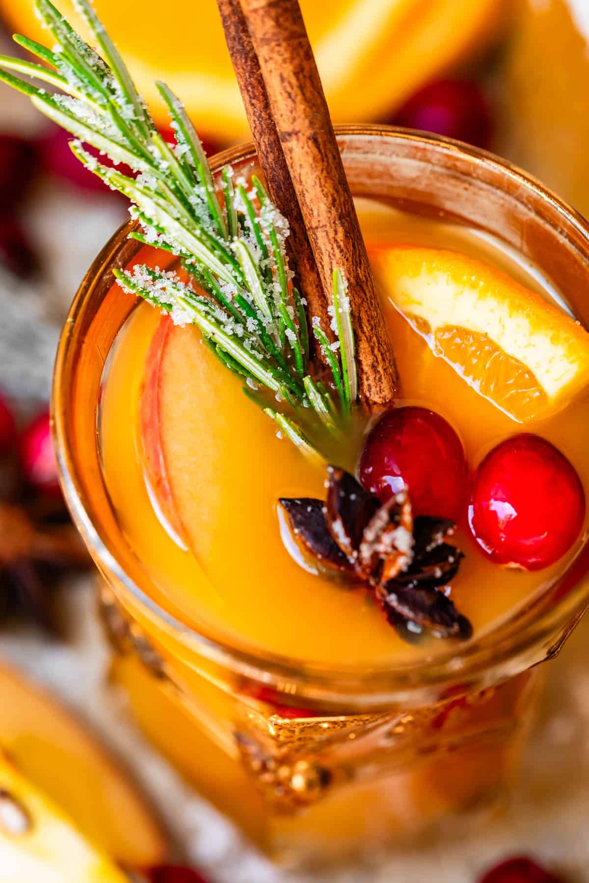 looking into the top of a glass of wassail topped with orange, cranberry, and more.