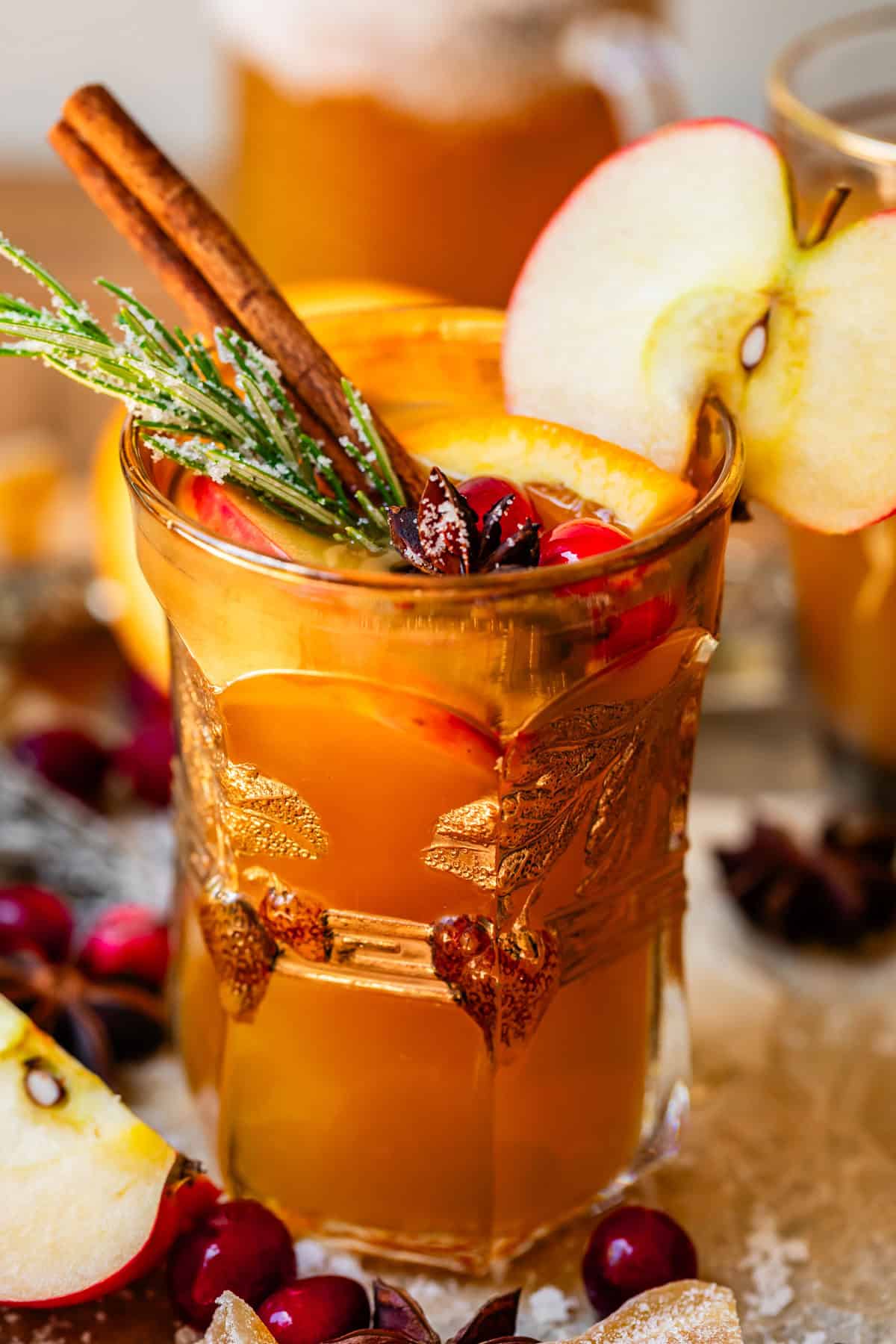 fancy glass filled with wassail and topped with sugared rosemary and cranberry.