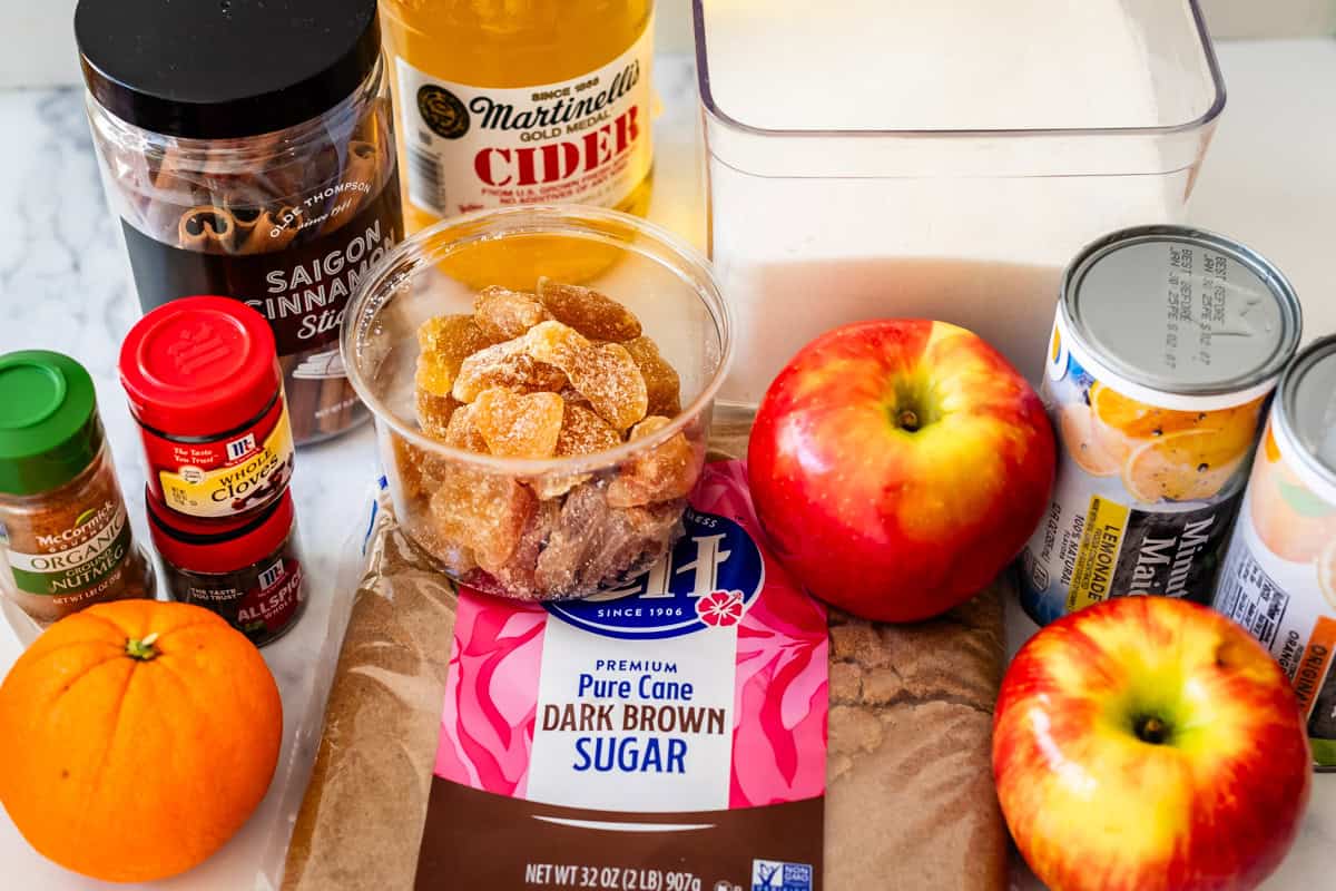 ingredients for wassail including apple cider, spices, frozen juice concentrate, and more.