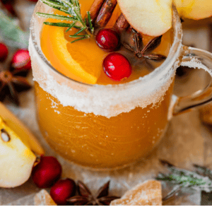 pinterest image of wassail in a sugar rimmed glass mug.