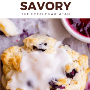 A close-up of a blueberry scone topped with white icing, with jam and another scone in the background. Above, text reads: Scones—Sweet or Savory. The Food Charlatan.