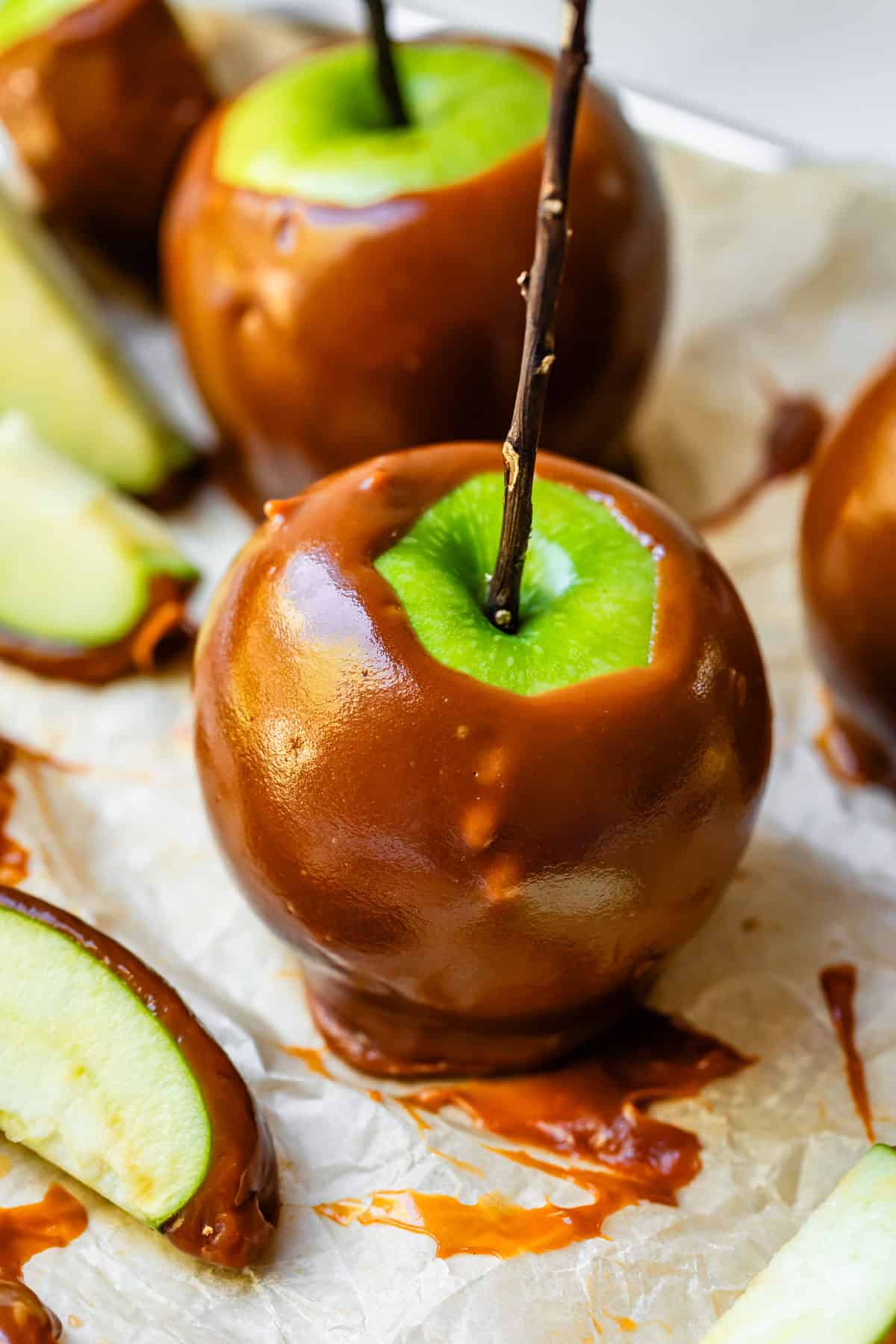 Green caramel apple on parchment paper.