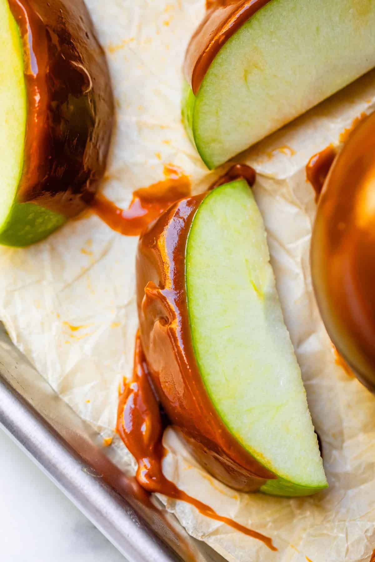 Caramel apple slices laid out on parchment paper.