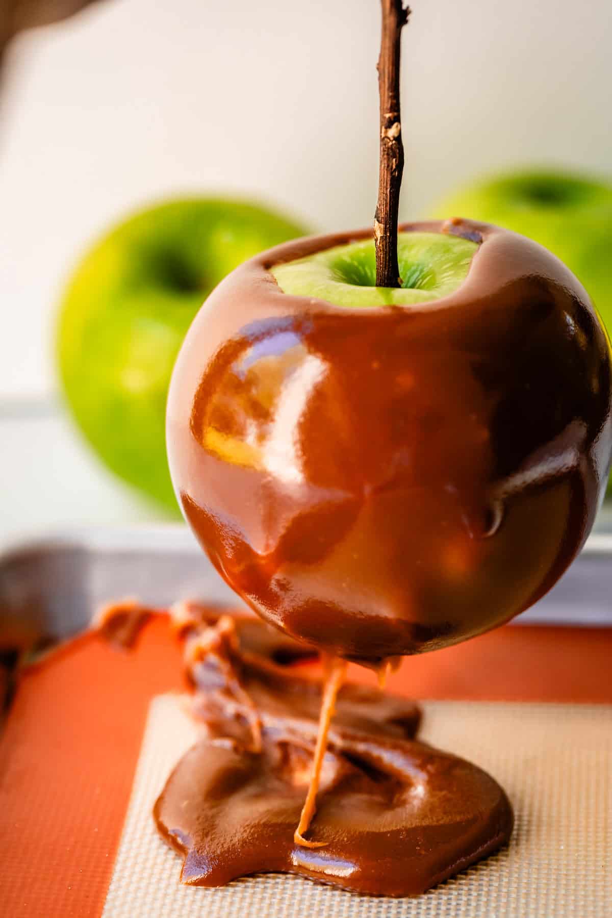 a caramel apple lifted from the silpat, showing extra caramel that can be added back to pan.