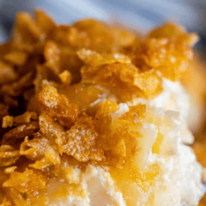 A close-up of funeral potatoes—a creamy, cheesy potato casserole topped with a crispy golden cornflake crust. The text FUNERAL POTATOES appears at the top of the image.