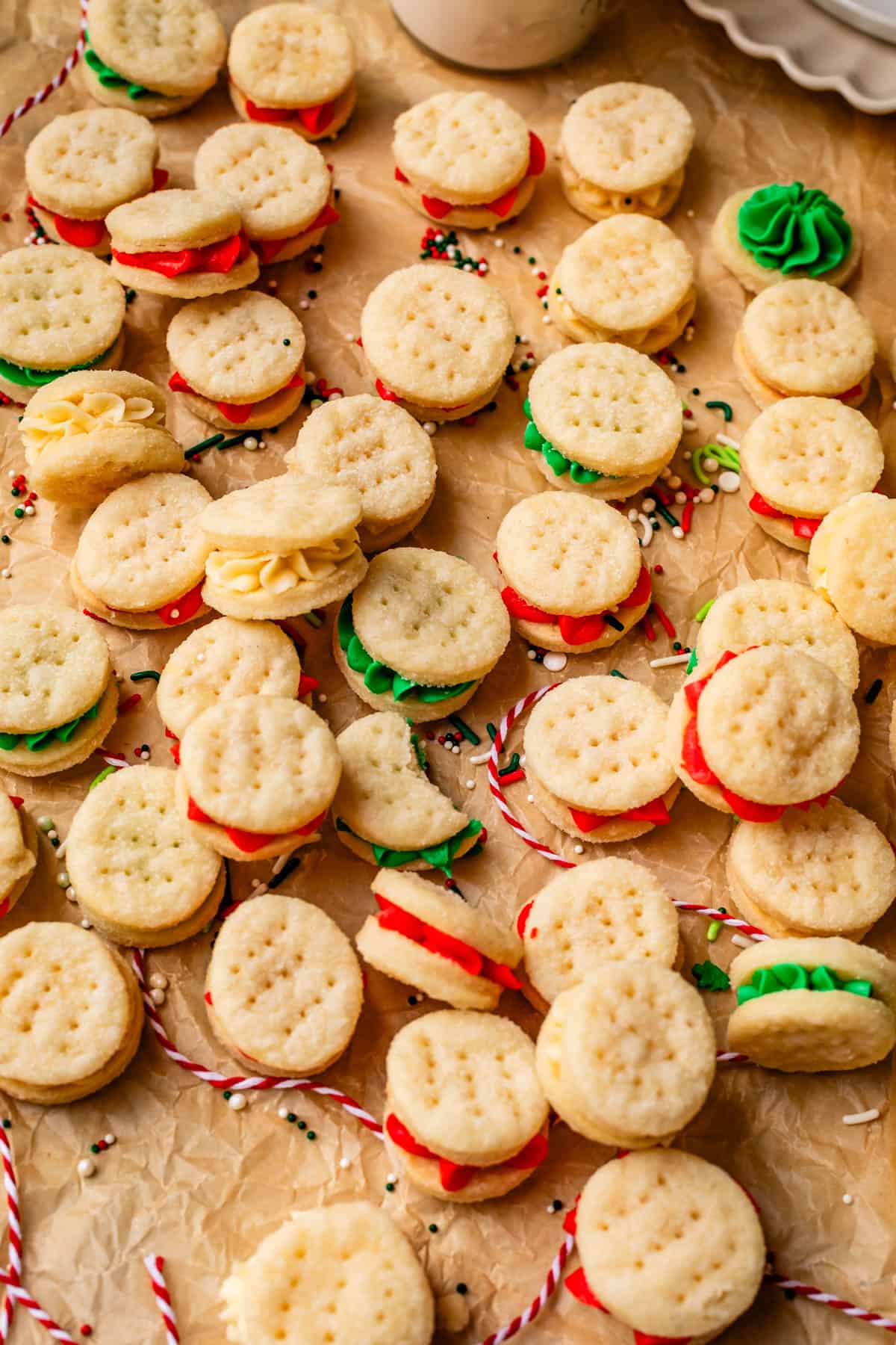 several dozen wafer cookies with red and green frosting in them on parchment paper.