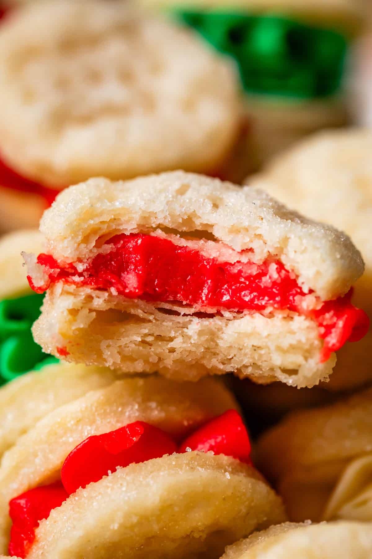 close up of a vanilla cream wafer cookie with red frosting and a bite taken from it.