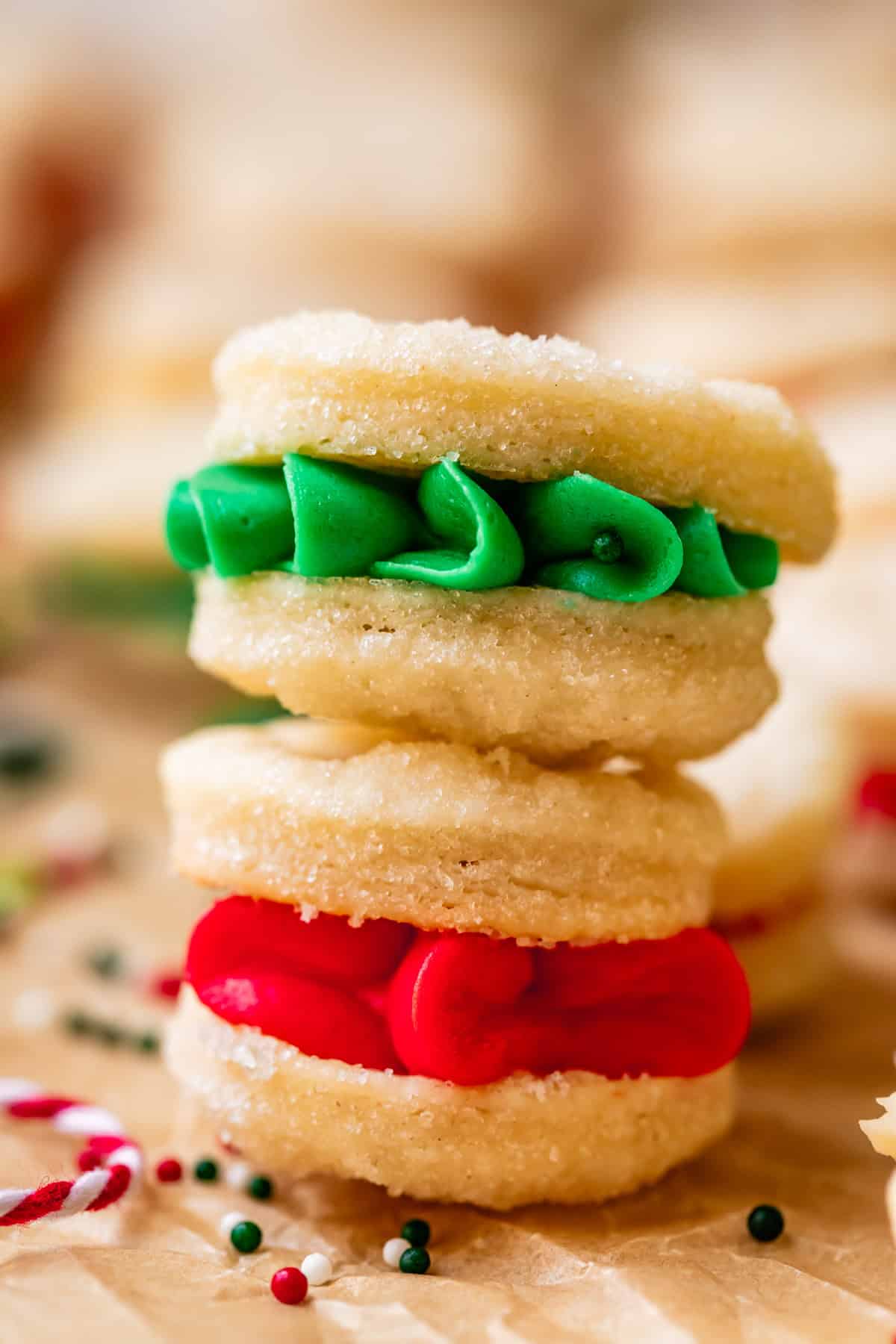 a green frosting filled cream wafer cookie stacked on another with red frosting.