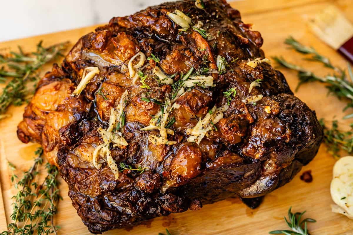 Prime rib roast fully cooked on cutting board with garlic board drizzled on.