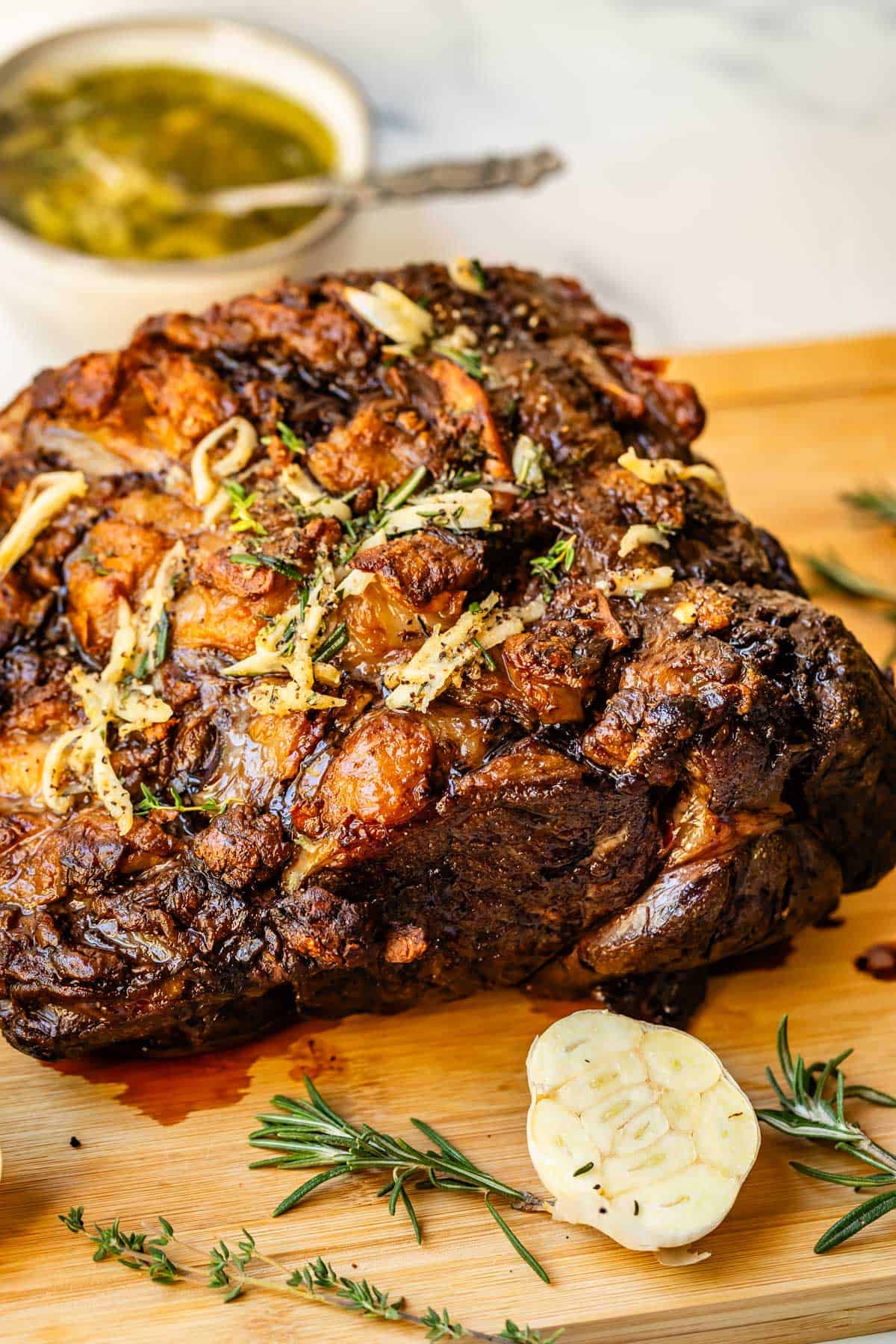 Beautifully seared prime rib roast on cutting board with sliced garlic in foreground.