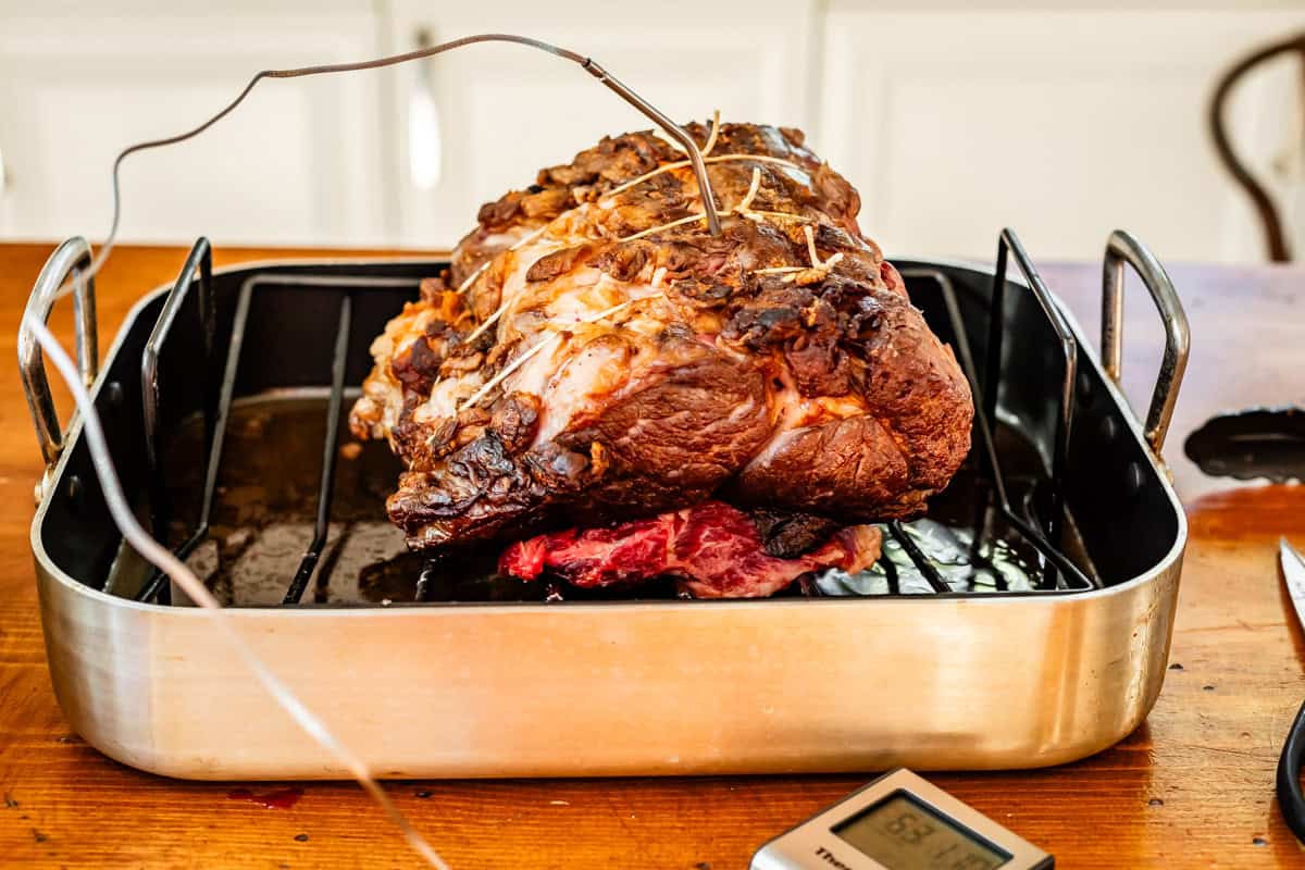 prime rib in a roasting pan with a thermometer probe stuck in the thickest part.