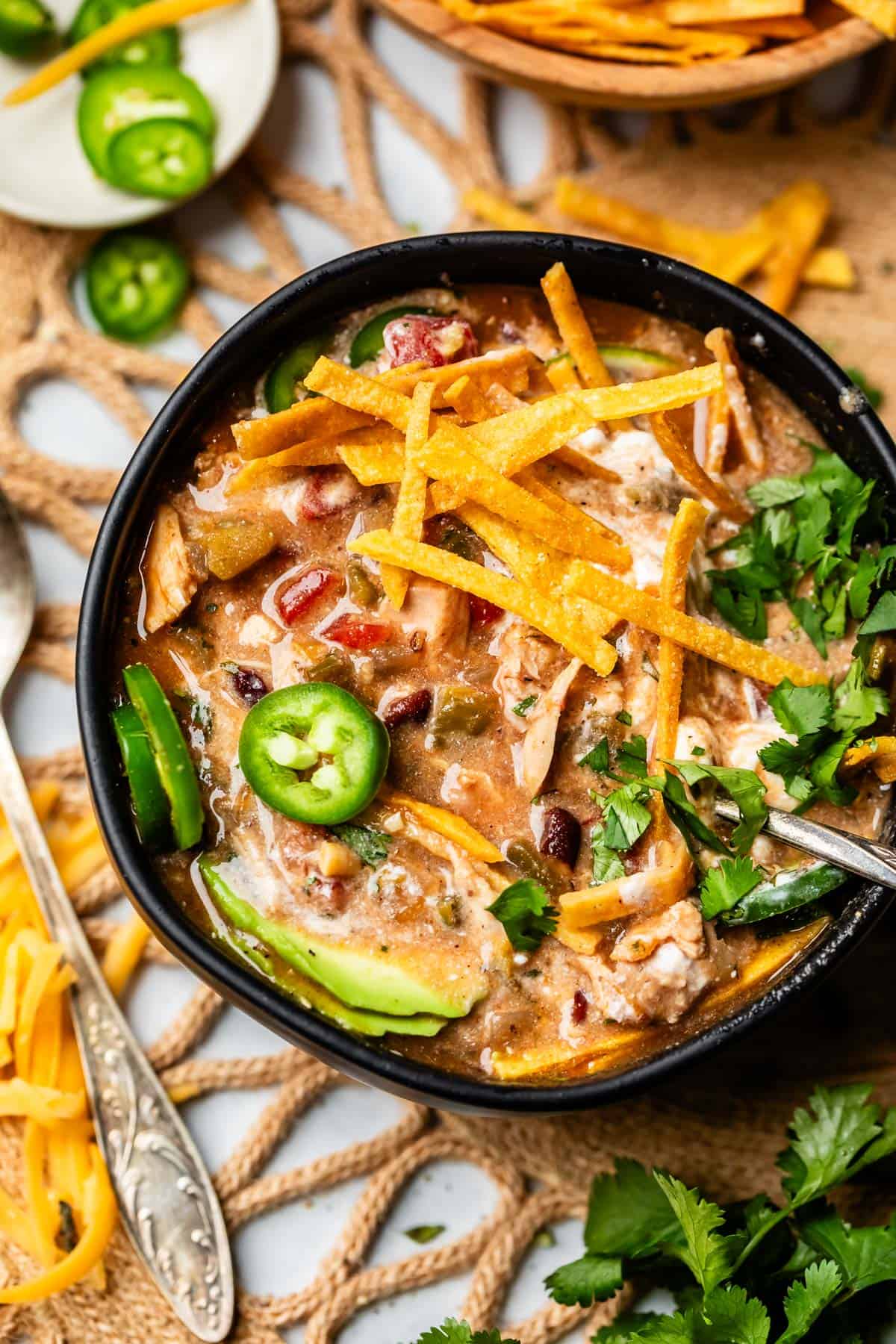 a bowl of tortilla chicken soup looking more creamy because of sour cream mixed in.