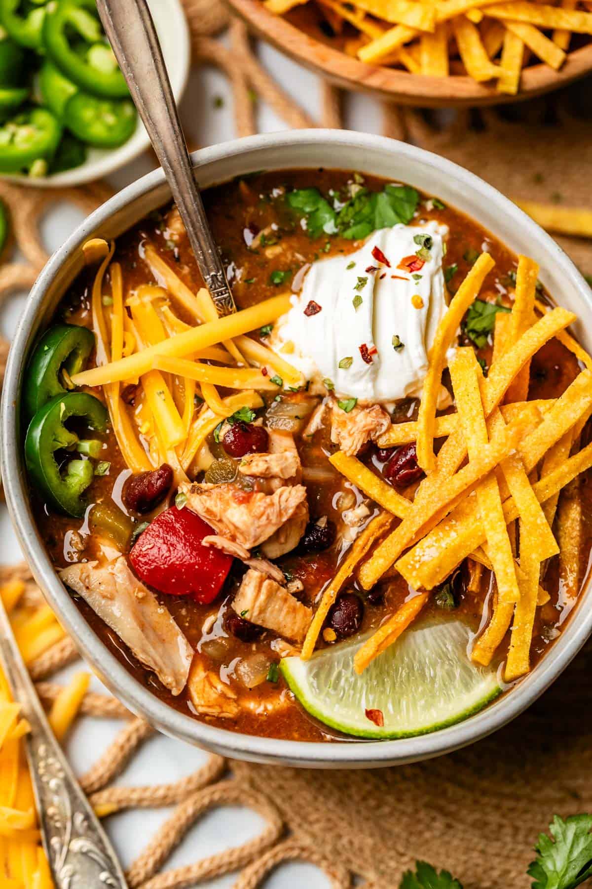 ceramic bowl filled to the brim with soup and toppings like tortilla strips and cheese.