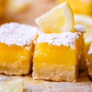 close up of a lemon bar with thick custard filling and a small lemon wedge garnish.