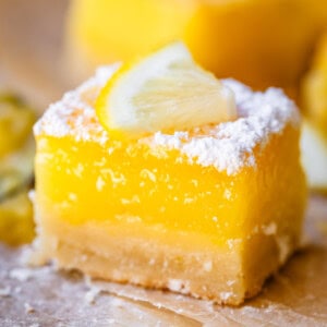 close up of a lemon bar perfectly balanced with crust, filling, and powdered sugar topping.