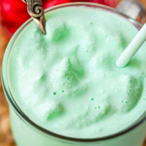 glass mug with shamrock shake with a spoon and a straw in it.