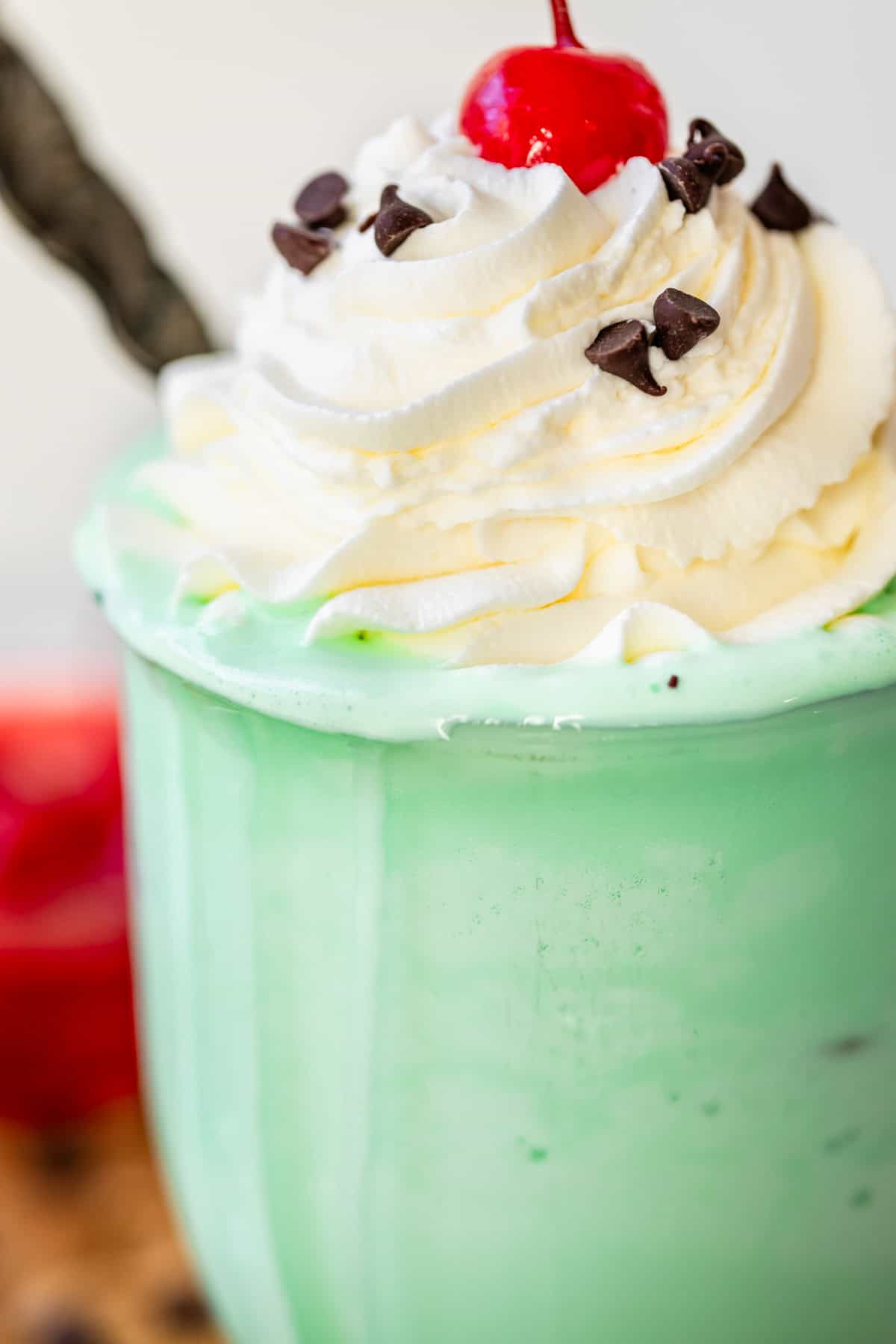glass filled with shake and topped with piped whipped cream, a cherry, and chocolate chips.