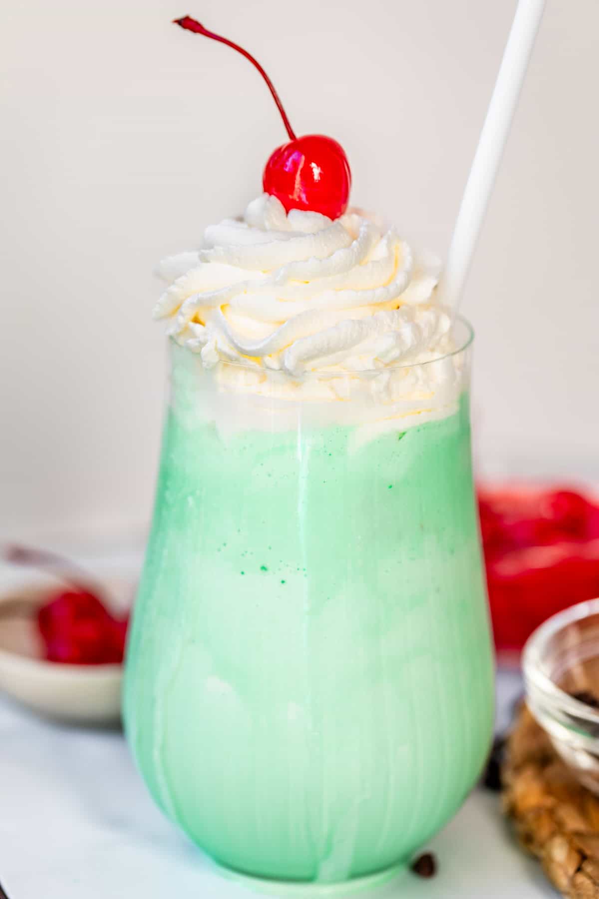 fluted glass cup with shamrock shake, topped with whipped cream and a cherry.