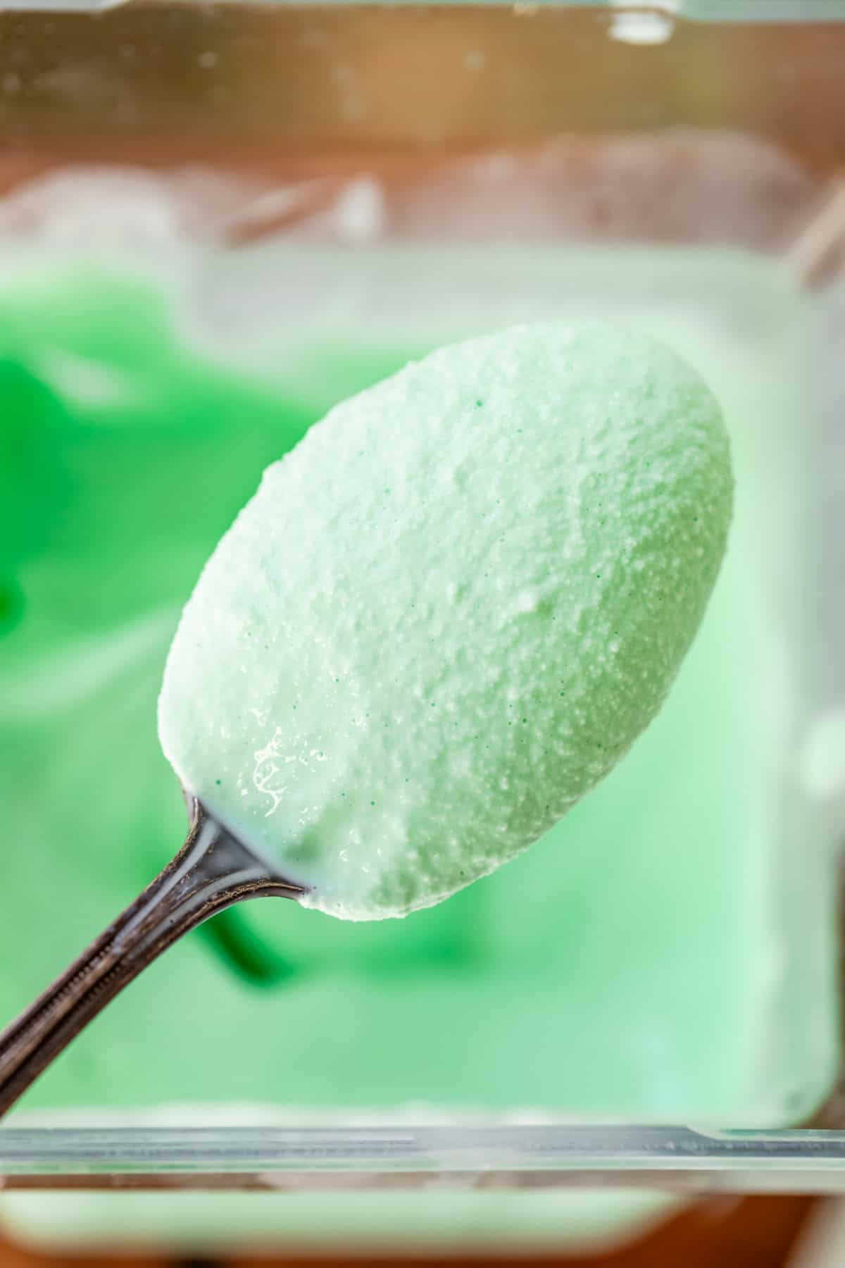 spoon holding a bite of super creamy shamrock shake over a blender with more shake.