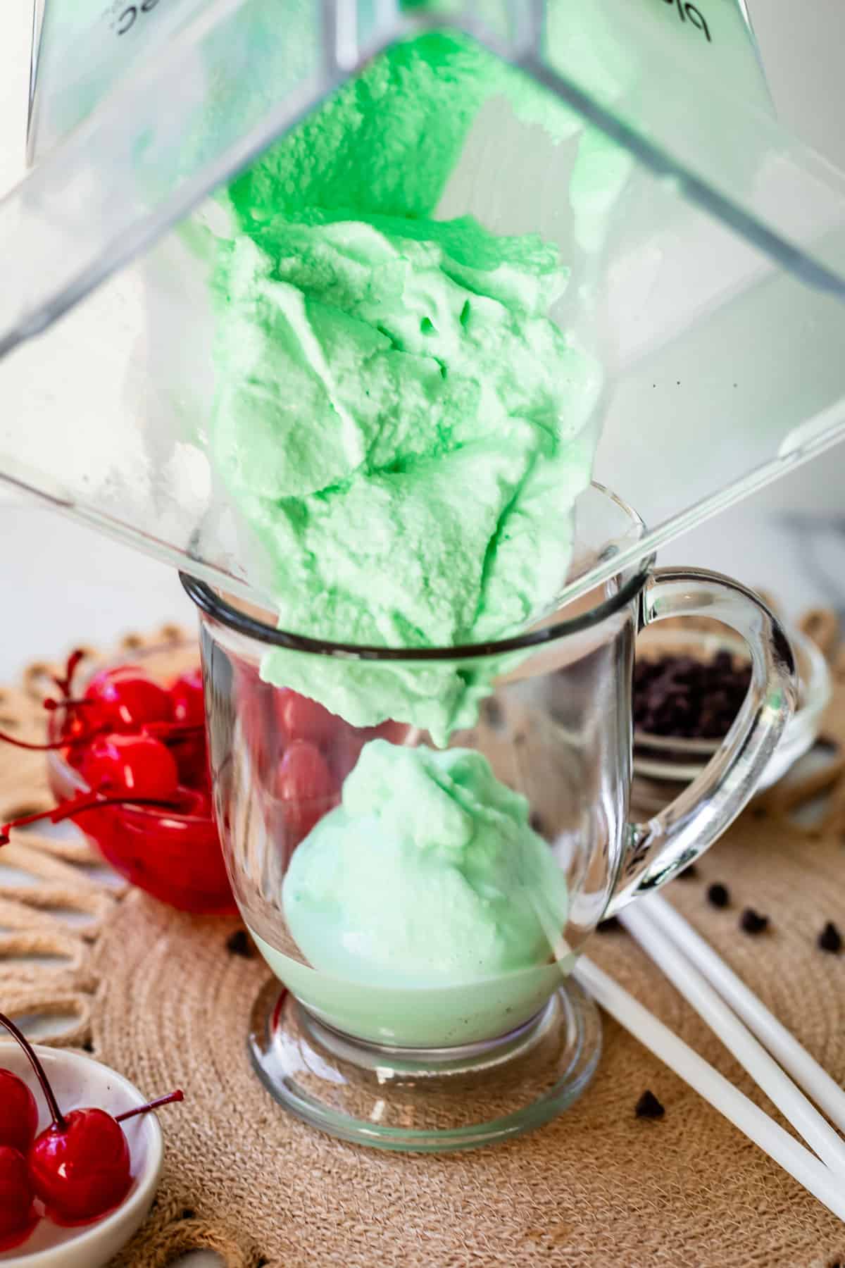 shamrock shake being poured from a plastic blender into a glass mug with a handle.