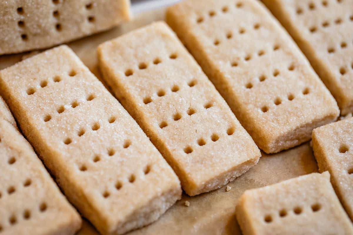 horizontal photo of shortbread finger cookies lined up in a row with fork marks.