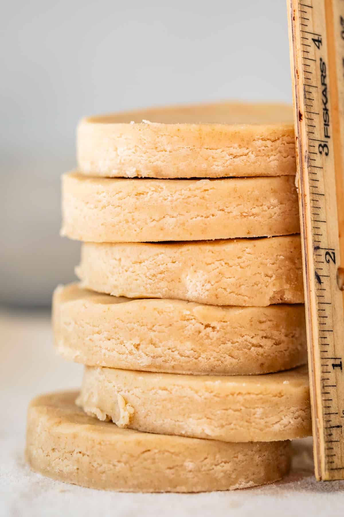 round raw cookies stacked with a ruler next to them showing how thick they are.