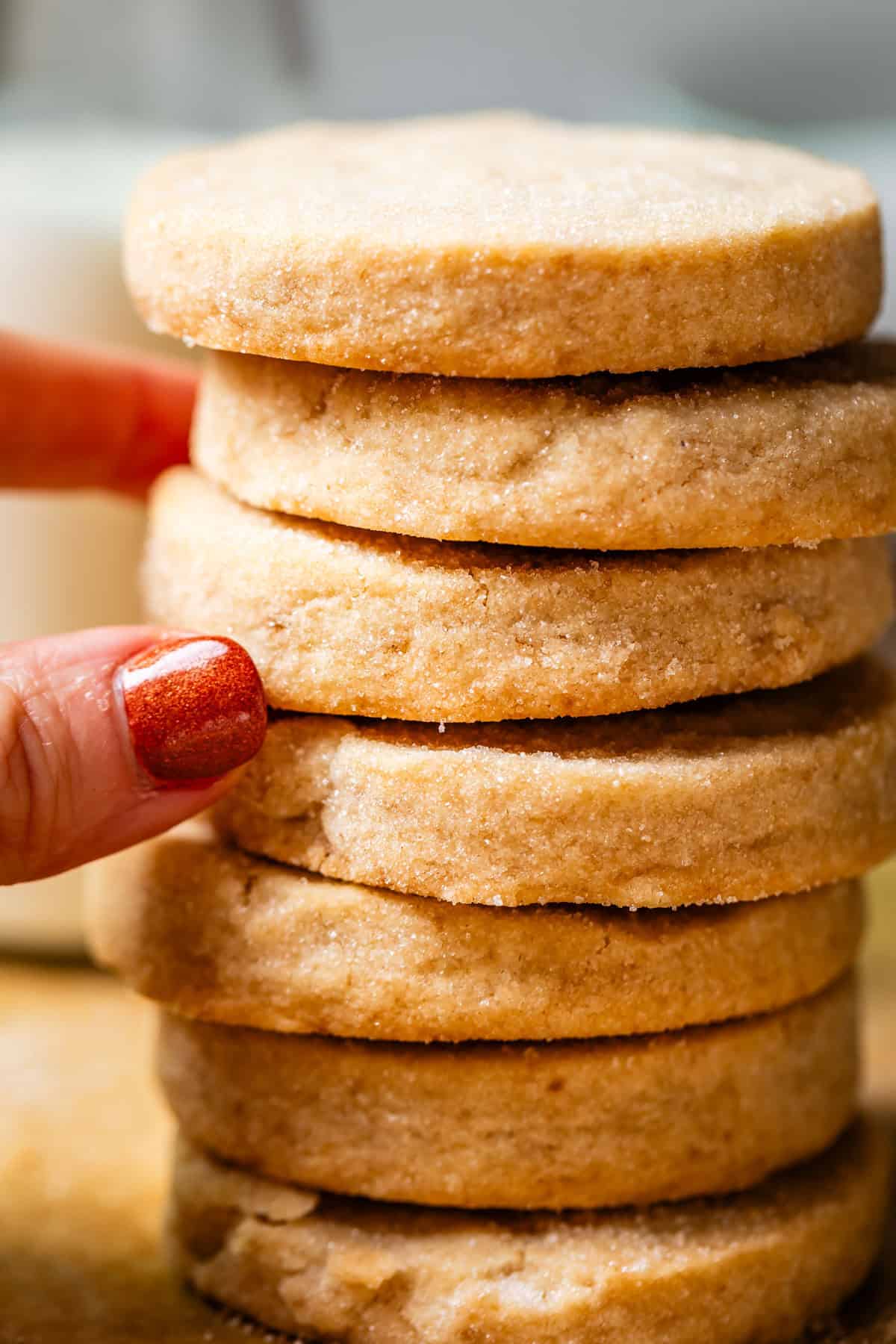 stack of round shortbread cookies with fingers pulling at the center cookies.