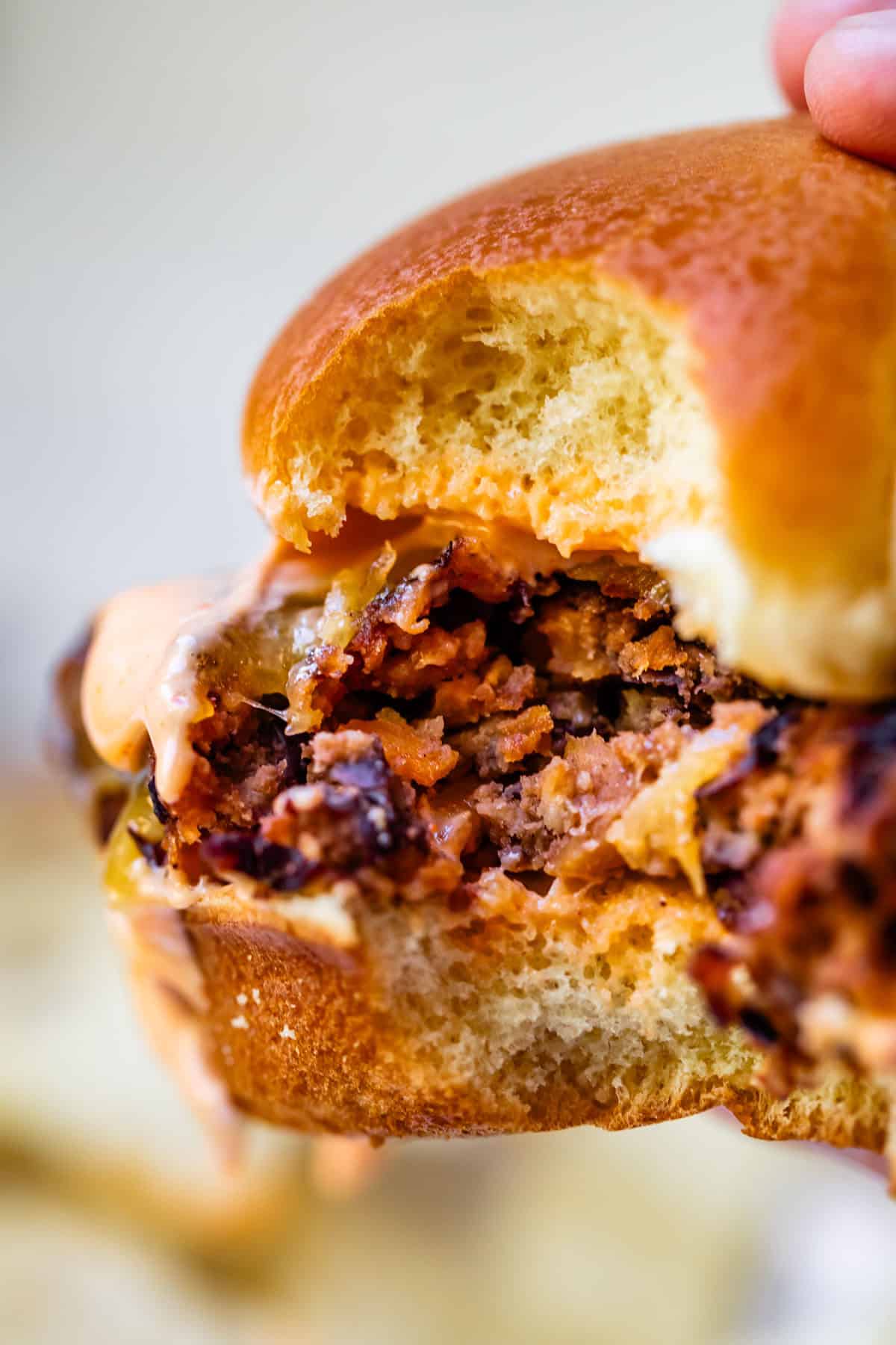 a black bean burger with cheese and sauce on a bun with a bite taken out of it.