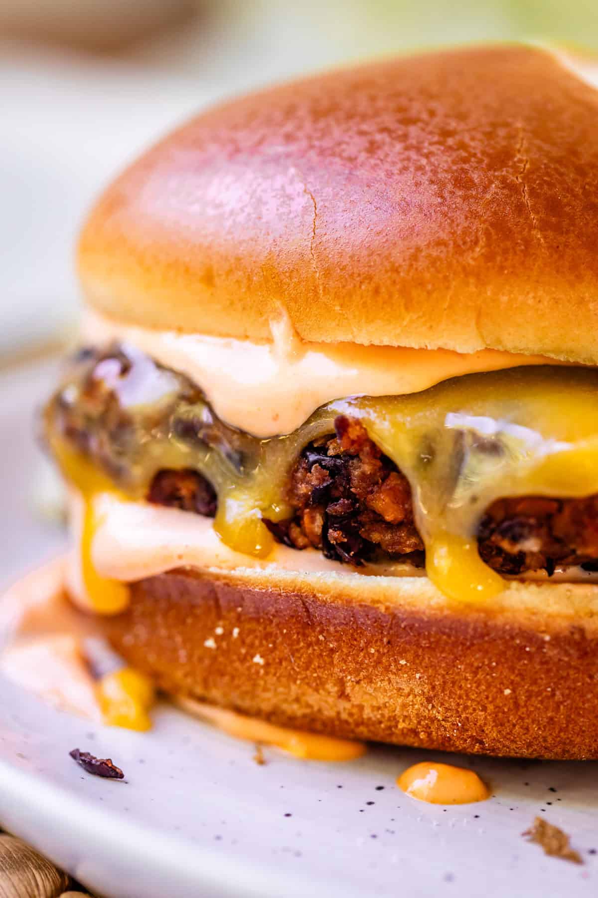a black bean burger on a bun with melted cheese and sriracha mayo.