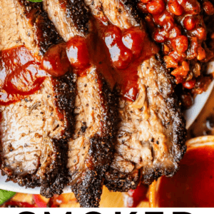 Three slices of brisket on a plate with sauce and beans.