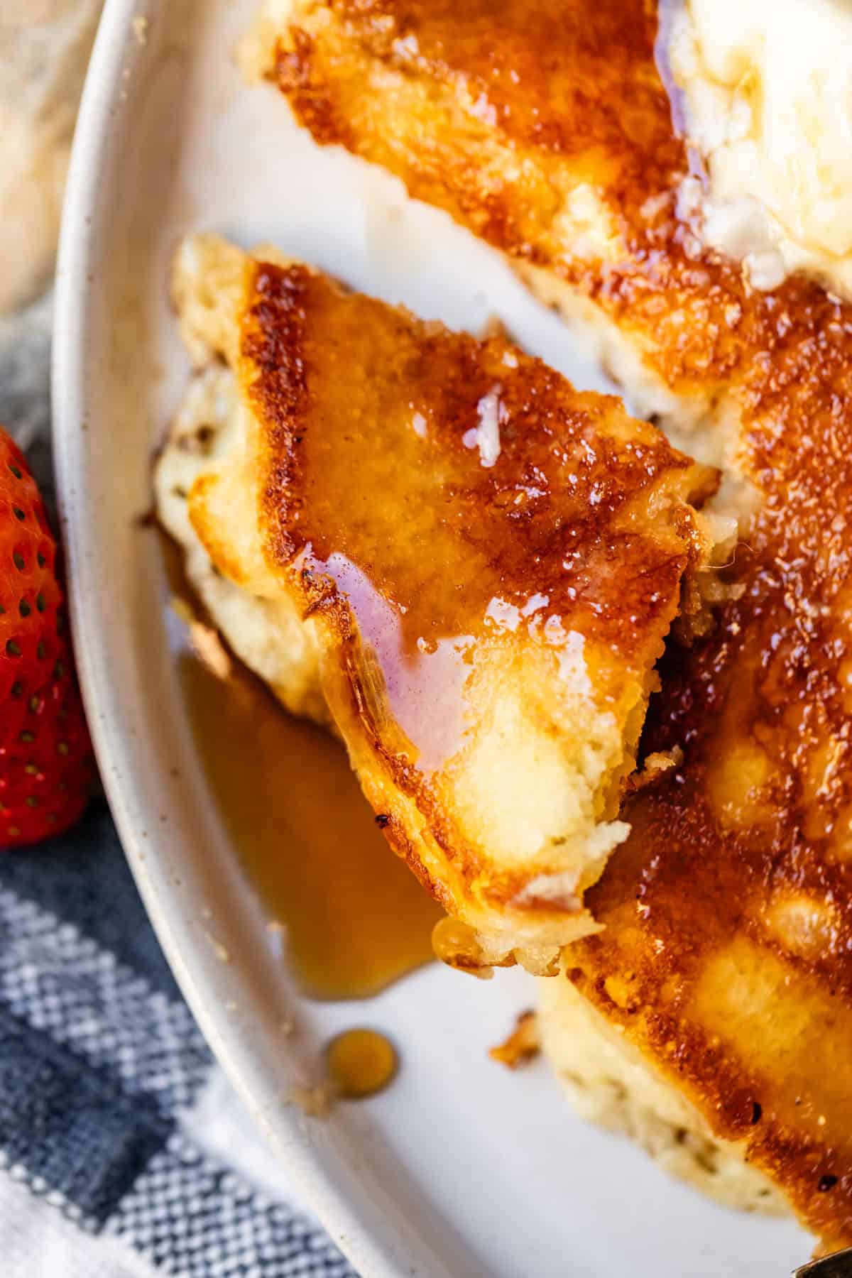 a cut piece of homemade pancake with butter and syrup.
