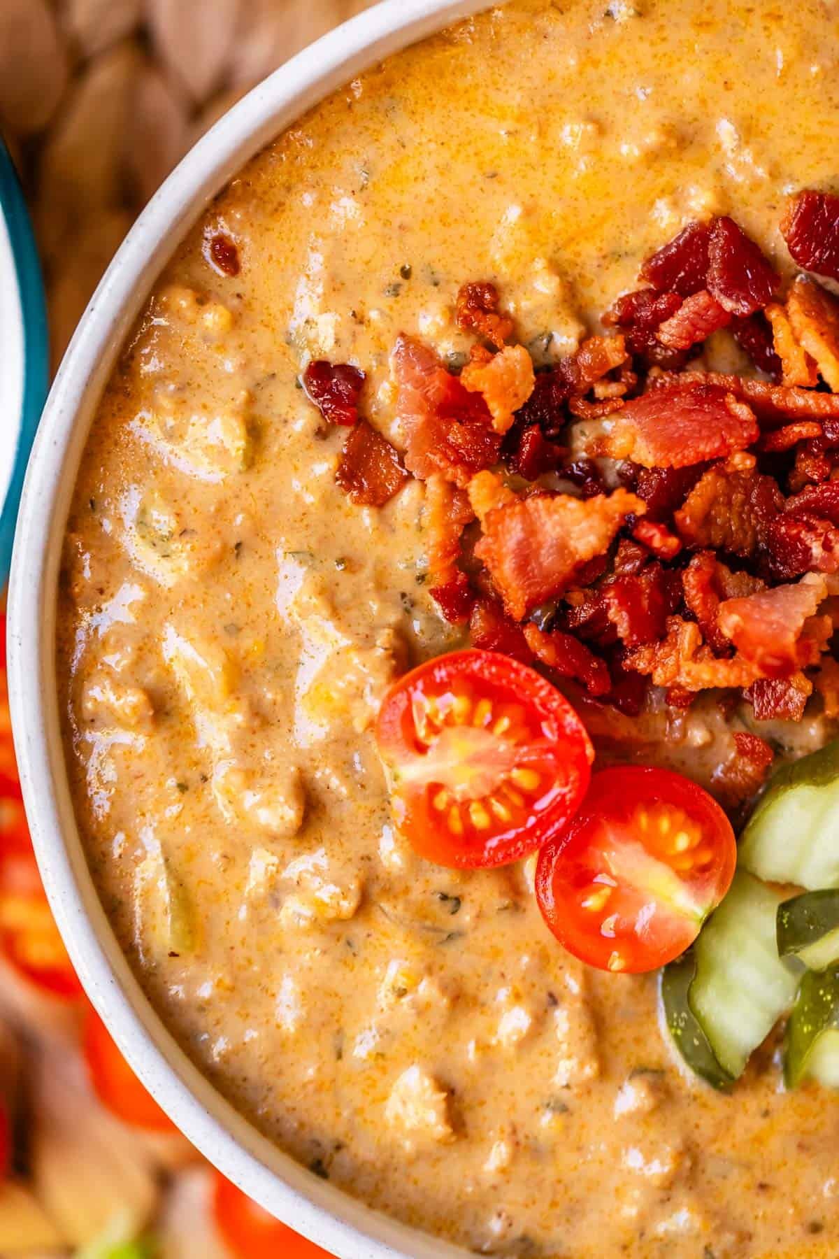 cheeseburger soup shot from above with tomatoes, bacon, and pickles.
