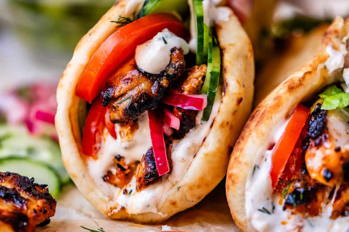 super close up image showing the juicy seared chicken, lettuce, tomato, and sauce in shawarma.