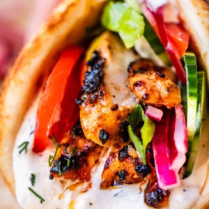 close up of chicken shawarma in naan with cucumber, onion, and garlic sauce.