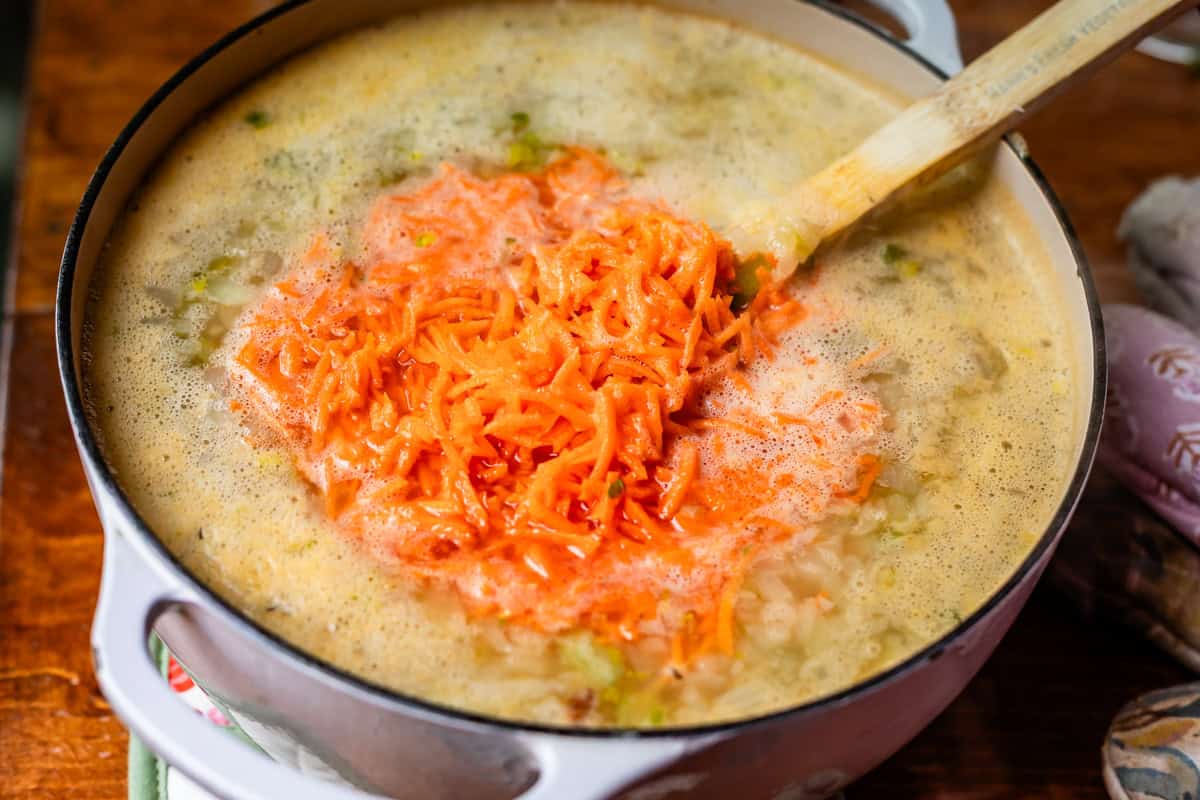 pot filled with soup and uncooked shredded carrots added to the pot.