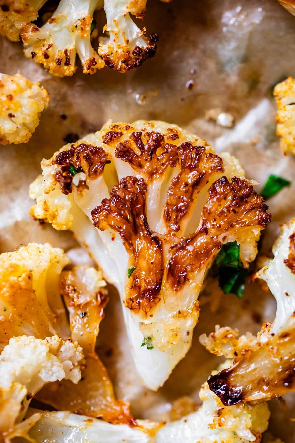 roasted crispy cauliflower floret on parchment paper on sheet pan.