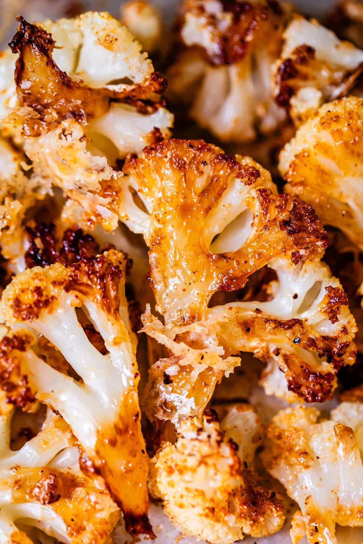 several perfectly roasted cauliflower florets topped with cheese.