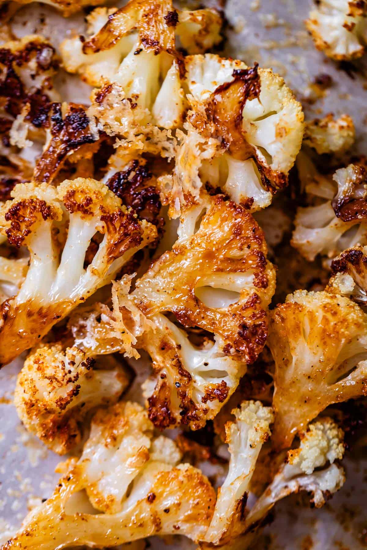 cheese crusted golden roasted cauliflower florets on a sheet pan.