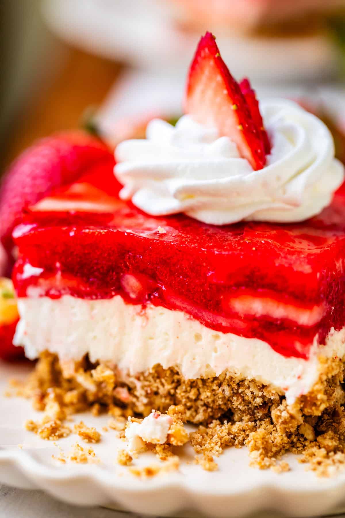 perfectly cut square of jello pretzel salad with whipped cream & strawberry garnish.