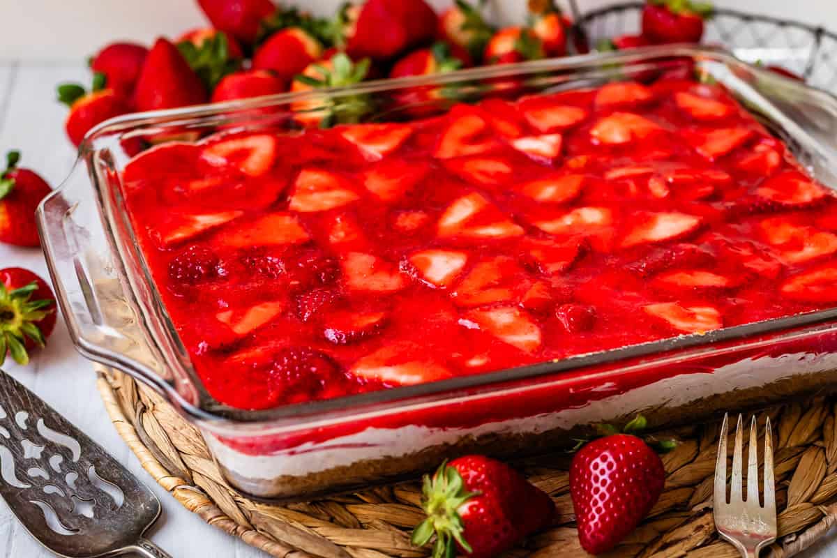 completed strawberry jello pretzel salad with strawberries around it.