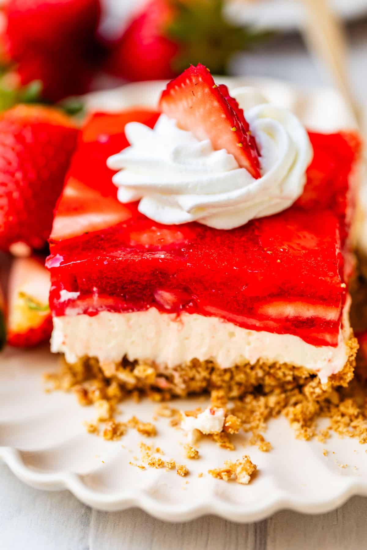 perfectly cut square of jello pretzel salad with whipped cream & strawberry garnish.
