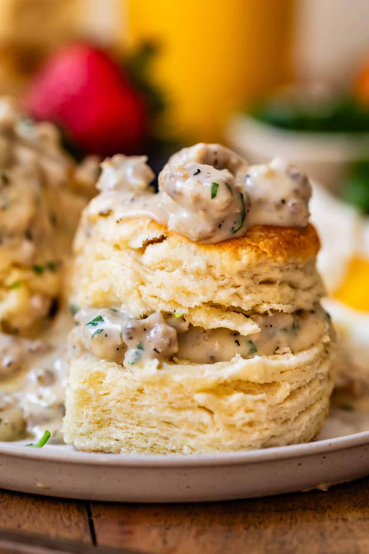 split biscuit with the pieces stacked and sausage gravy on top and between on a plate.